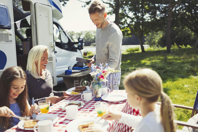 Family eating breakfast at table outside sunny motor home — Stock Photo