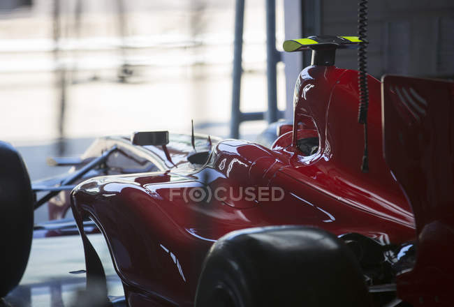 Red formula one race car in repair garage — Stock Photo