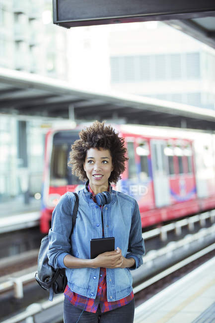 Woman holding digital tablet in train station — Stock Photo