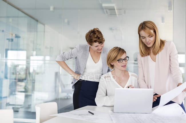 Жінки-архітектори на ноутбуці оглядають креслення в конференц-залі зустрічі — стокове фото