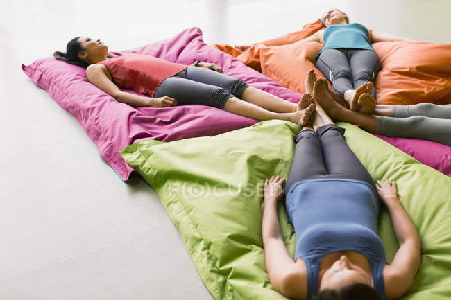 Women laying on cushions in restorative yoga gym studio — Stock Photo