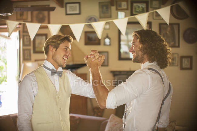 Bridegroom and best man holding hands in domestic room — Stock Photo