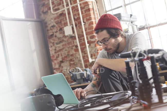 Male computer programmer working at laptop in workshop — Stock Photo