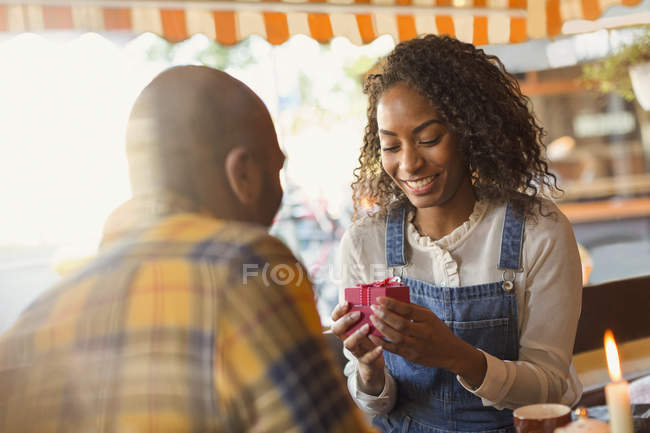 Jeune homme donnant boîte cadeau à petite amie dans le café — Photo de stock
