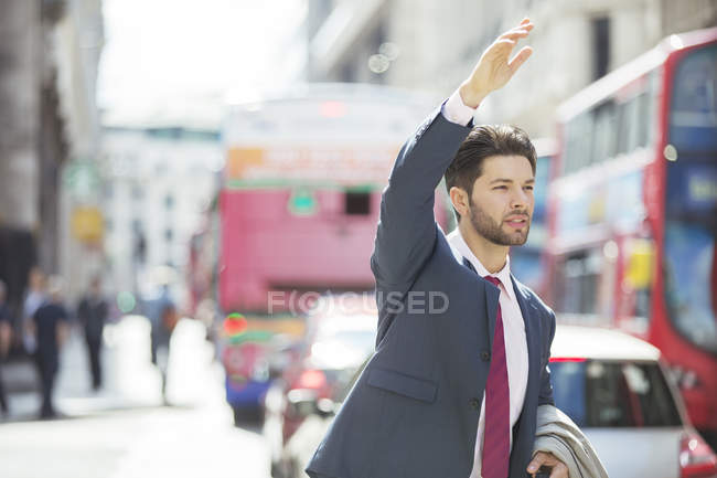 Businessman hailing taxi in city — Stock Photo