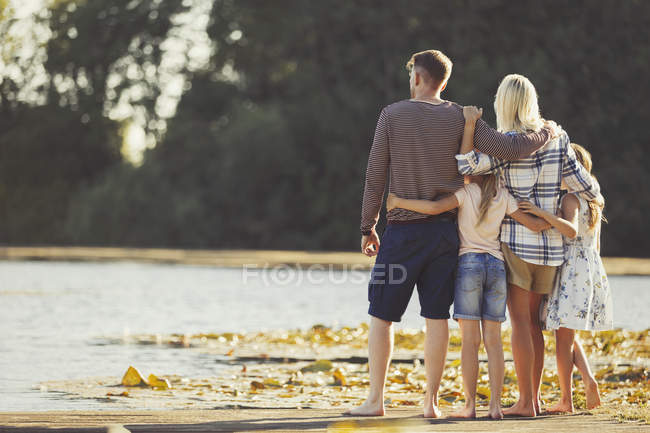 Abraço familiar ao lado do lago ensolarado — Fotografia de Stock