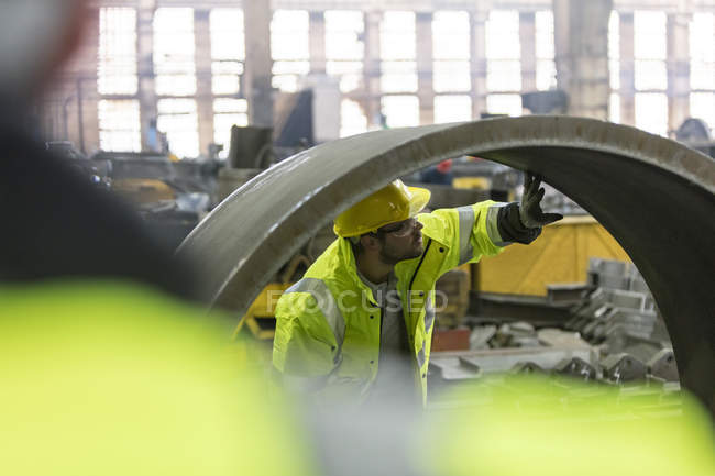 Trabajador de acero examinando tubería en fábrica - foto de stock