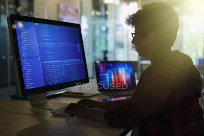 Мальчик-ученик программирует за компьютером в темном классе — стоковое фото