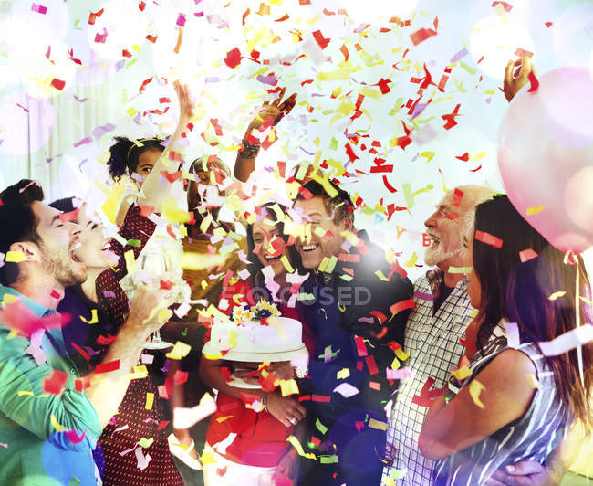 Family throwing confetti celebrating birthday party with cake — Stock Photo