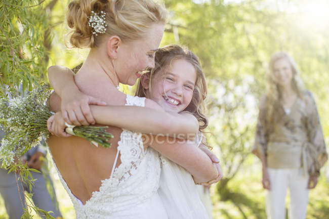 Bride embracing bridesmaid at wedding reception in domestic garden — Stock Photo