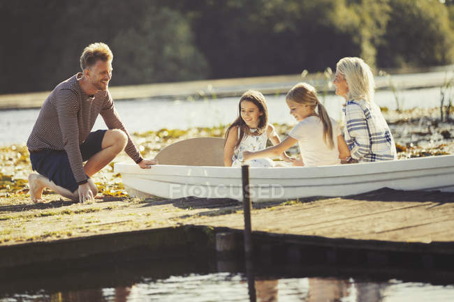 Família em canoa na ensolarada doca do lago — Fotografia de Stock