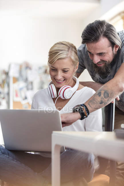 Professionnels du design souriants travaillant sur un ordinateur portable dans un bureau — Photo de stock