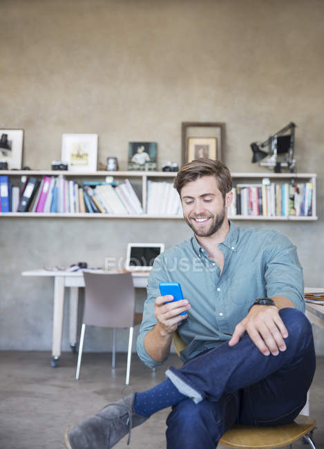 Young blonde man sitting with mobile phone in studio — Stock Photo