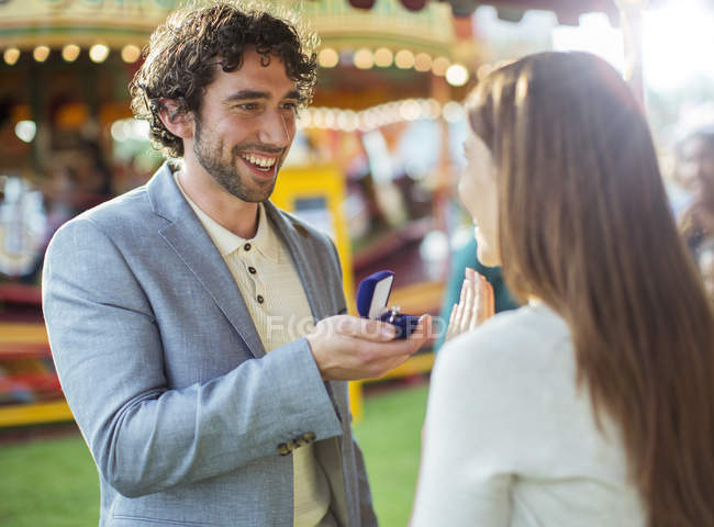 Homme proposant à petite amie dans le parc d'attractions — Photo de stock