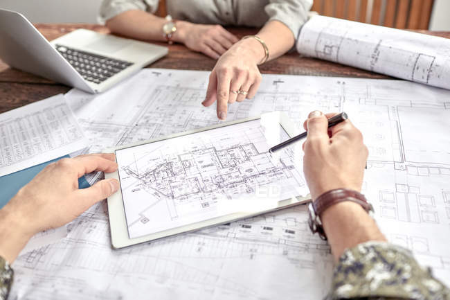 Architects reviewing and discussing complex digital blueprint in meeting — Stock Photo