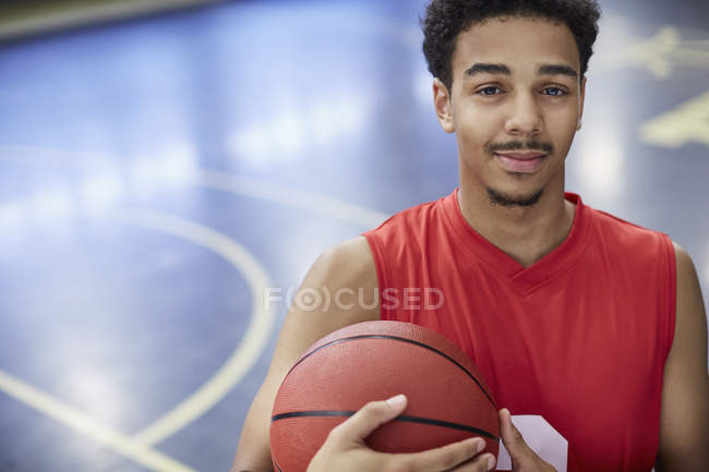 Porträt selbstbewusster junger männlicher Basketballer, der Basketball auf dem Court hält — Stockfoto