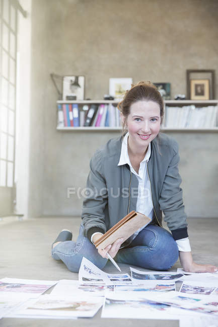 Retrato de una joven sentada en el suelo y trabajando - foto de stock