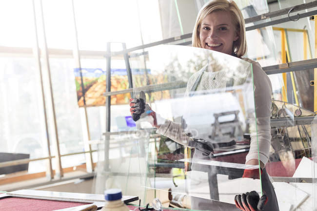 Retrato sorrindo vitral artista levantando vidro em estúdio — Fotografia de Stock