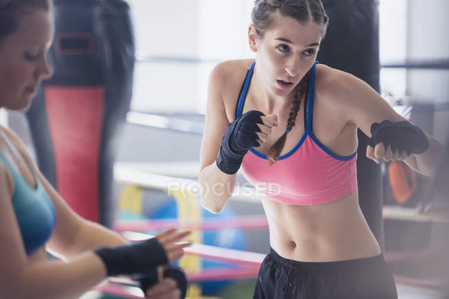 Решительная, жесткая молодая боксерша теневой бокс в тренажерном зале — стоковое фото