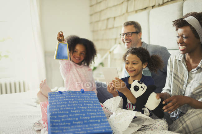 Regalo di compleanno multi-etnico di apertura familiare sul letto — Foto stock