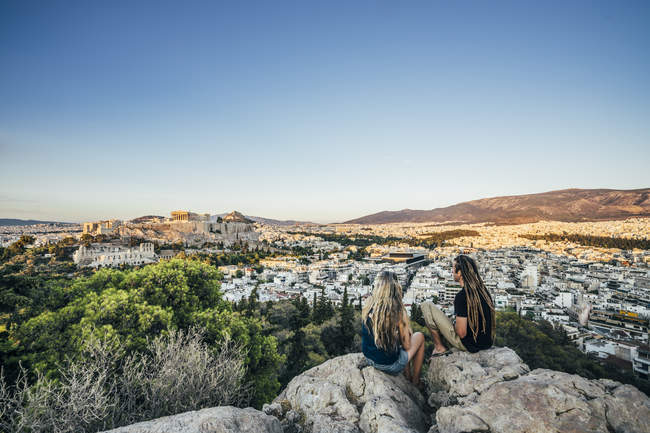 Couple assis sur des rochers surplombant le paysage, Athènes, Grèce — Photo de stock