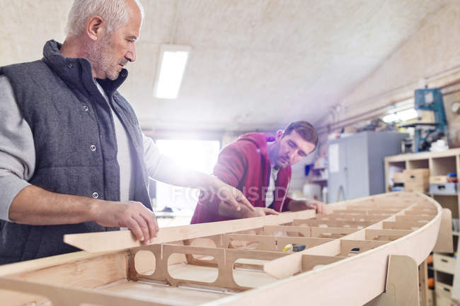 Плотники мужского пола собирают деревянные лодки в мастерской — стоковое фото