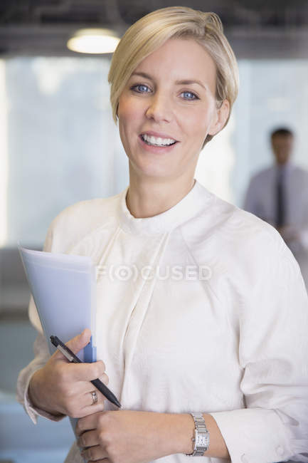 Porträt lächelnde, selbstbewusste Geschäftsfrau mit Papierkram — Stockfoto