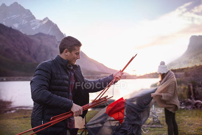 Giovane coppia che lancia tenda al campeggio sul lago di montagna — Foto stock