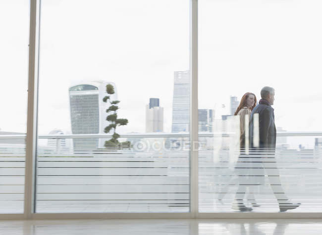 Businessman and businesswoman walking on urban highrise balcony with city view — Stock Photo