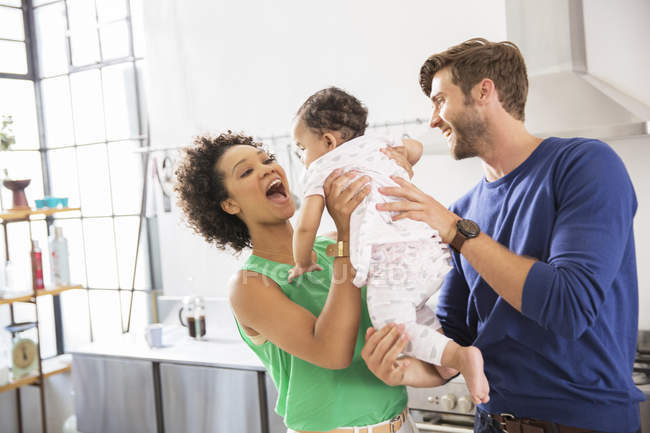 Pais felizes segurando sua filha bebê na cozinha doméstica — Fotografia de Stock