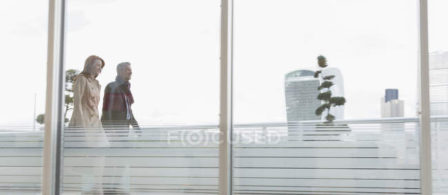 Businessman and businesswoman walking on urban highrise balcony — Stock Photo