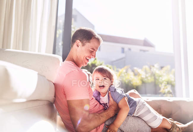 Zärtlicher Vater hält kleinen Sohn in sonnigem Wohnzimmer — Stockfoto