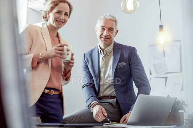 Portrait smiling, confident business people drinking coffee and working at laptop in office — Stock Photo
