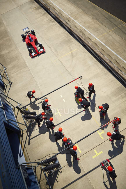 Pit crew listo para acercarse a la fórmula de un coche de carreras en pit lane - foto de stock