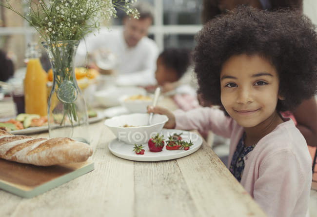Retrato sorrindo menina comendo morangos na mesa de café da manhã — Fotografia de Stock