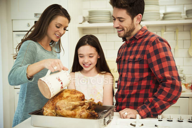 Family preparing Christmas dinner turkey in kitchen — Stock Photo