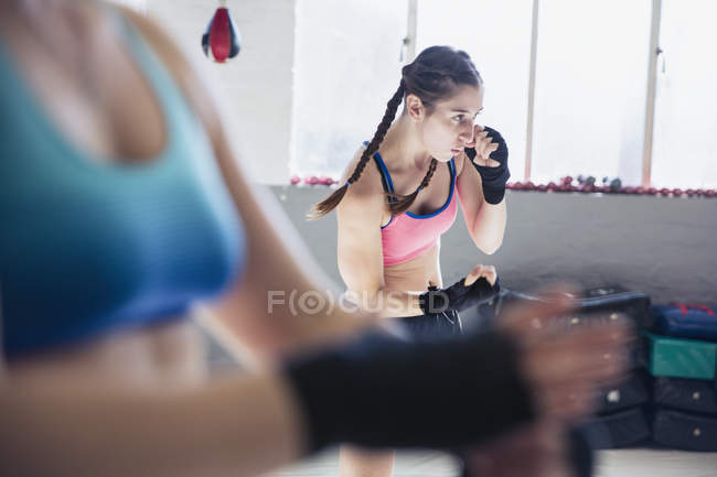 Entschlossene junge Boxerin im Schattenboxen im Fitnessstudio — Stockfoto