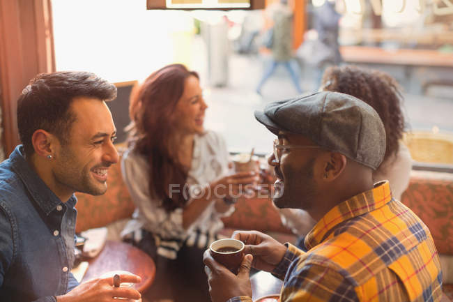 Друзья разговаривают и пьют кофе в кафе — стоковое фото