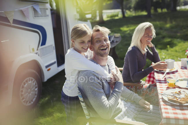 Glücklicher, liebevoller Vater und Tochter, die sich vor dem sonnigen Wohnmobil umarmen — Stockfoto