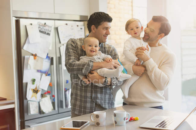 Чоловічі гей-батьки тримають синів на кухні — стокове фото