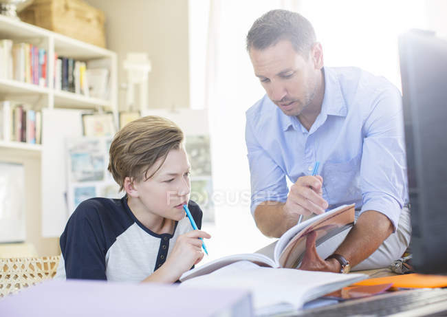 Padre ayudando a hijo adolescente con su tarea - foto de stock