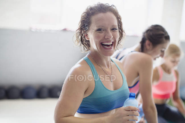 Портрет усміхнений, сміється жінка п'є воду і відпочиває пост тренування в спортзалі — стокове фото