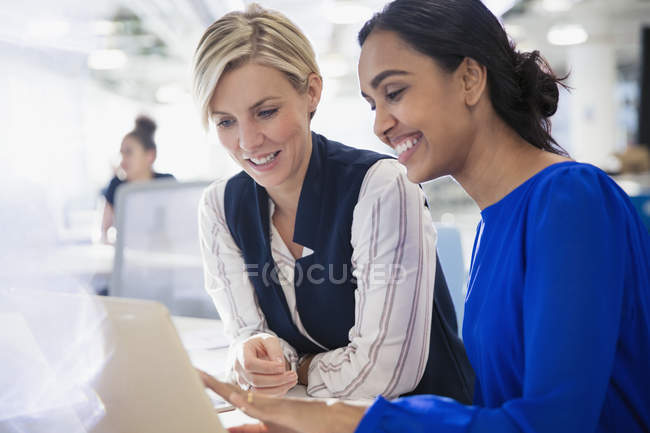 Улыбающиеся деловые женщины используют ноутбук вместе — стоковое фото