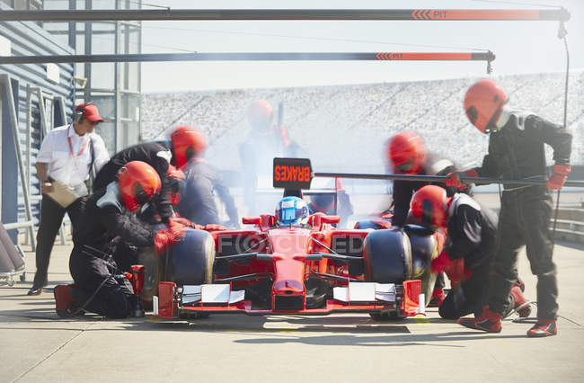 Tripulação de poço trabalhando em um carro de corrida de fórmula um em pit lane — Fotografia de Stock