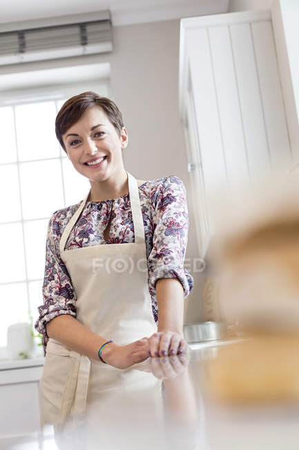 Портрет улыбающейся брюнетки в фартуке на кухне — стоковое фото