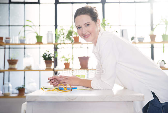 Portrait of young woman leaning on kitchen counter — Stock Photo