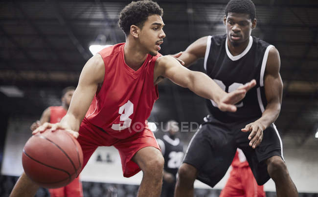Young male basketball player dribbling the ball, protecting from defender in basketball game — Stock Photo