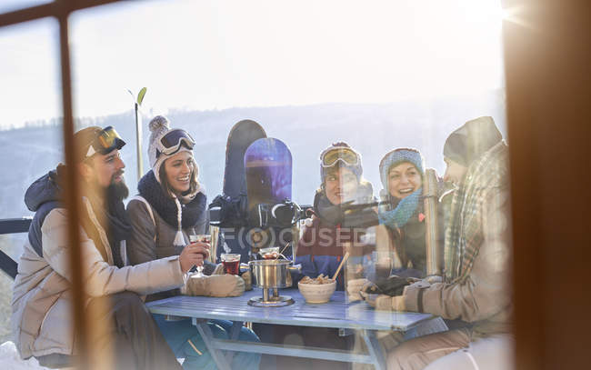 Snowboarder friends drinking and eating at balcony table apres-ski — Stock Photo