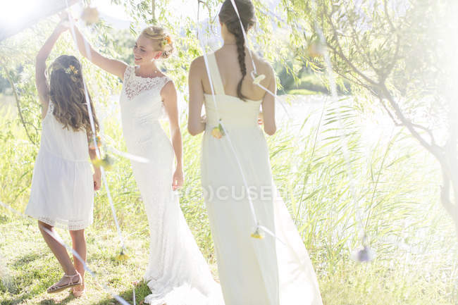 Невеста и подружка невесты играют с украшениями в саду во время свадебного приема — стоковое фото