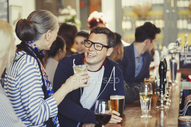 Friends talking and drinking beer at bar — Stock Photo